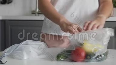 年轻女子将蔬菜从塑料袋移到厨房木桌上可重复使用的网袋。 零废物