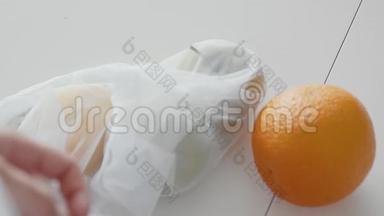 在木桌上的厨房里，用苹果、橘子和柠檬把女人打开的网状购物袋合上。 <strong>零废物</strong>