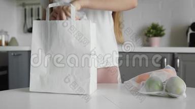 在木制桌子上的厨房里，把带水果的年轻女人包装纸购物袋合上。 <strong>零废物</strong>家园和生态