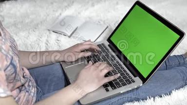 这位年轻女子使用笔记本<strong>电脑</strong>和键盘打字，工作场所在家里。 带<strong>绿</strong>色<strong>屏幕</strong>的笔记本<strong>电脑</strong>