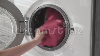 女用手从洗衣机里取出粉红色的衣服。 去装洗衣机。 把衣服装进洗衣机。 负荷