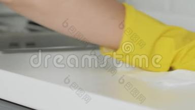 家庭主妇戴黄色手<strong>套用</strong>白色抹布和洗涤剂洗桌子。