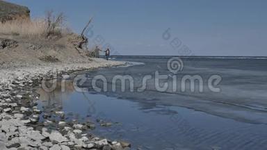 一对年轻夫妇沿着冰<strong>封</strong>的河流的岸边散步，阳光明媚的春天