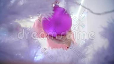 年轻女子挂在粉红色的圣诞树球上，享受着节日的精神。