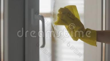 家庭主妇戴黄色手套，用黄色<strong>抹布</strong>和<strong>洗</strong>涤剂清<strong>洗</strong>窗户。
