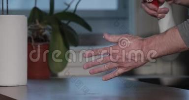 男人正在用消毒器清洗双手，在喷瓶、卷纸巾、消毒手部皮肤期间