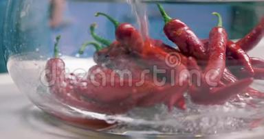 新鲜的热红辣椒用清水清洗和清洗玻璃花瓶。 素食健康营养食品。