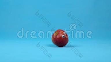 有眼睛的红苹果慢慢滚动。 带蓝色背景卷的苹果。 慢动作。