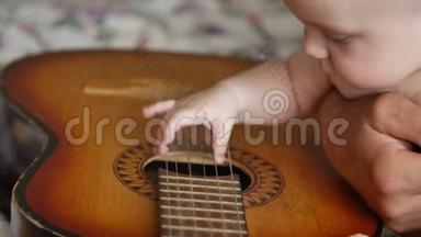 小男孩触摸和拖着一串老式吉他。 婴幼儿和幼儿概念.. 前方视野近