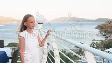 十几岁的女孩走在户外<strong>露台</strong>上，有海和山的<strong>景观</strong>。 夏日阳台上的幸福女孩抚摸扶手