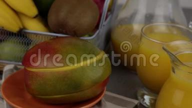 一杯果汁。黄色清爽的夏季饮料。新鲜芒果汁，橙汁。桌子上的水果篮。新鲜水果和ju