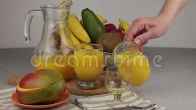 在玻璃杯中倒入脱脂剂中的果汁。 一杯果汁。 黄色清爽夏日饮品.. 鲜芒果汁，橙汁.. 果果