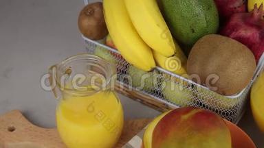 果篮和一杯果汁。新鲜芒果汁，橙汁。桌子上的水果篮。新鲜水果和果汁