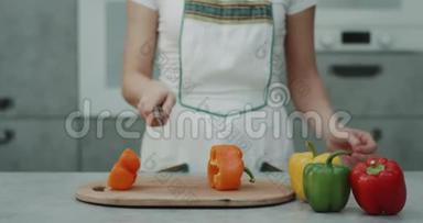 在现代厨房的视频中，一个女人在镜头前剪了一个橙色的甜椒特写。 4k