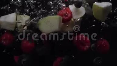 蓝莓、蓝莓、黑莓和苹果碎片在黑色背景下<strong>落入</strong>水中。 慢动作。 有机有机