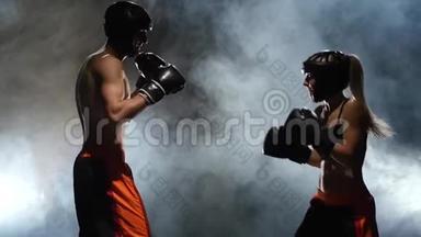 女拳击手是由一个男人教的。 拳击在<strong>擂台</strong>上打拳。 慢动作。 烟雾背景