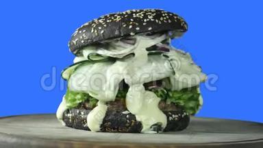 一个多汁的大汉堡，里面有一个绿色的小面包，里面撒着芝麻和青菜，里面还有一块肉馅