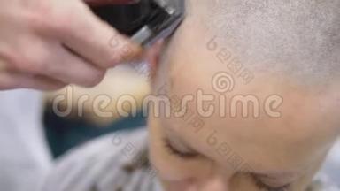 理发师用电动剃须刀把头发剃在一个女人的头上。 快关门。 <strong>剪发</strong>的时候