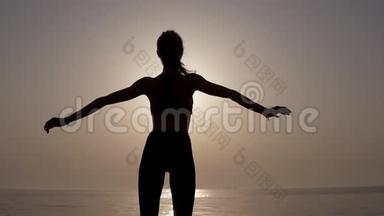 一个身材苗条、身材匀称的女孩站在海边，令人叹为观止。 就像早晨的日出。 坚强和有抱负