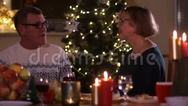 成熟的男人和女人在一张<strong>桌子上</strong>说话，<strong>桌子上放</strong>着蜡烛，背景是圣诞树灯。 第一次