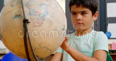 高加索学童在4k教室课桌上学习地球仪的前景